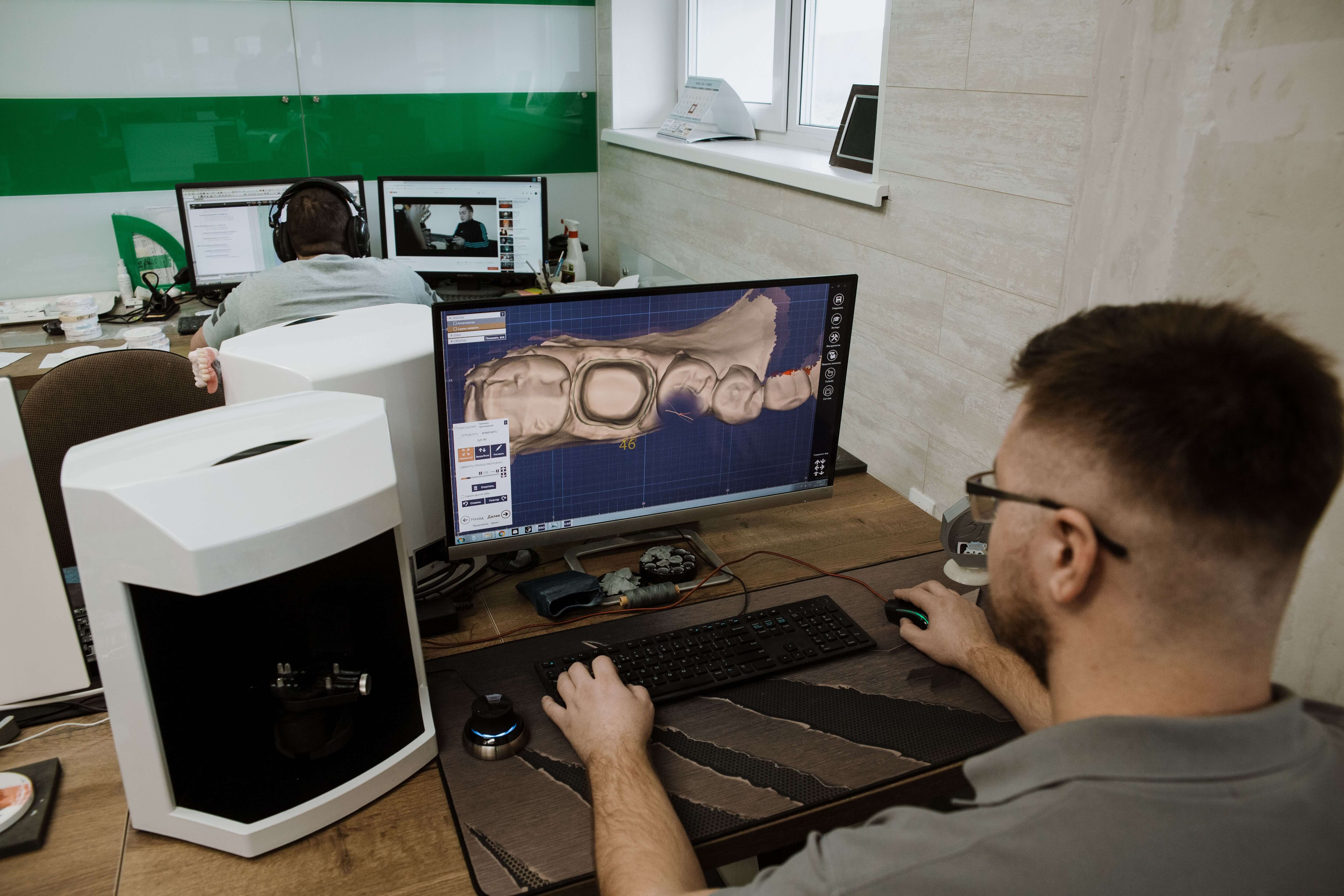 Dental technician designing a 3D dental model on a monitor