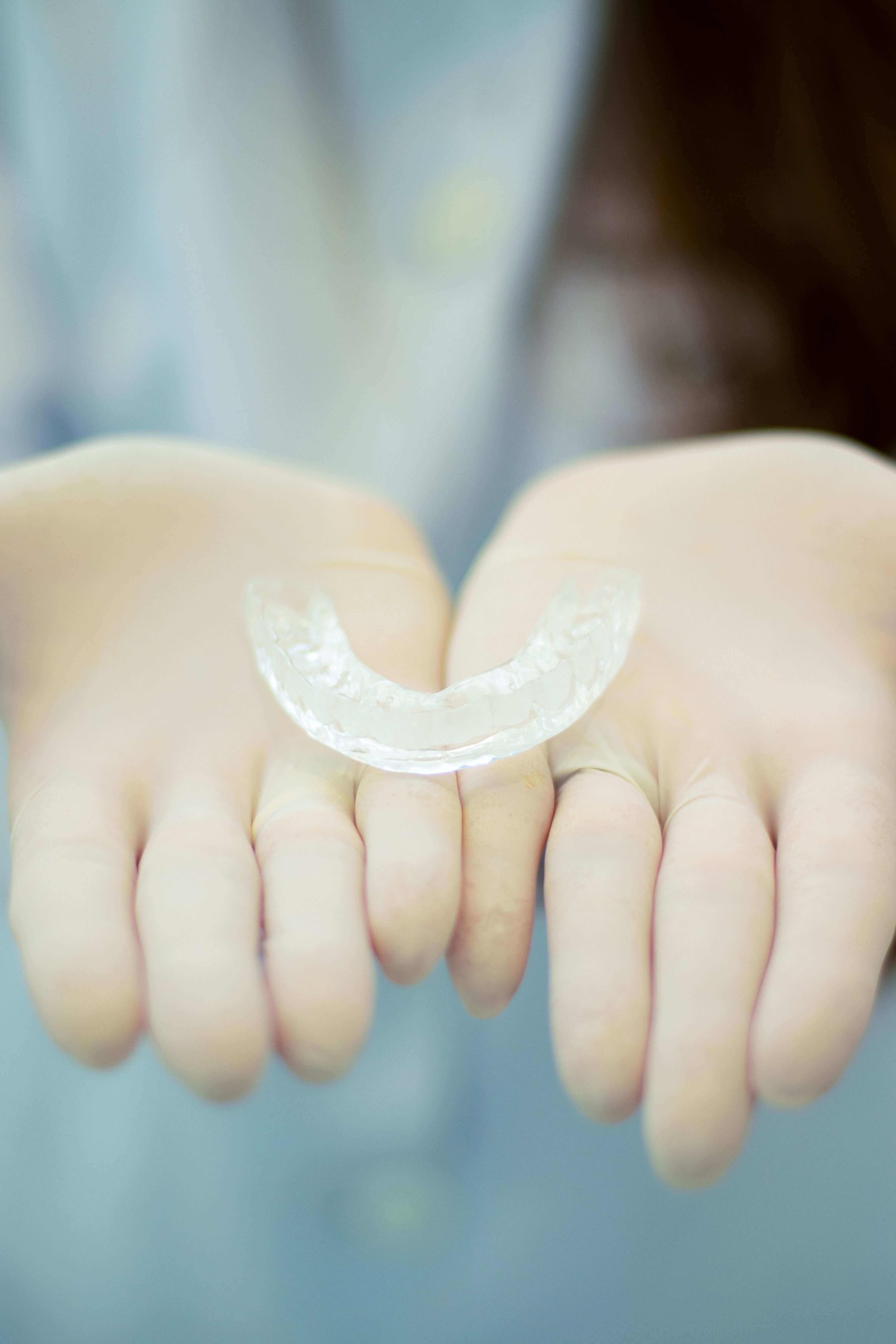 Gloved hands holding a clear orthodontic aligner tray